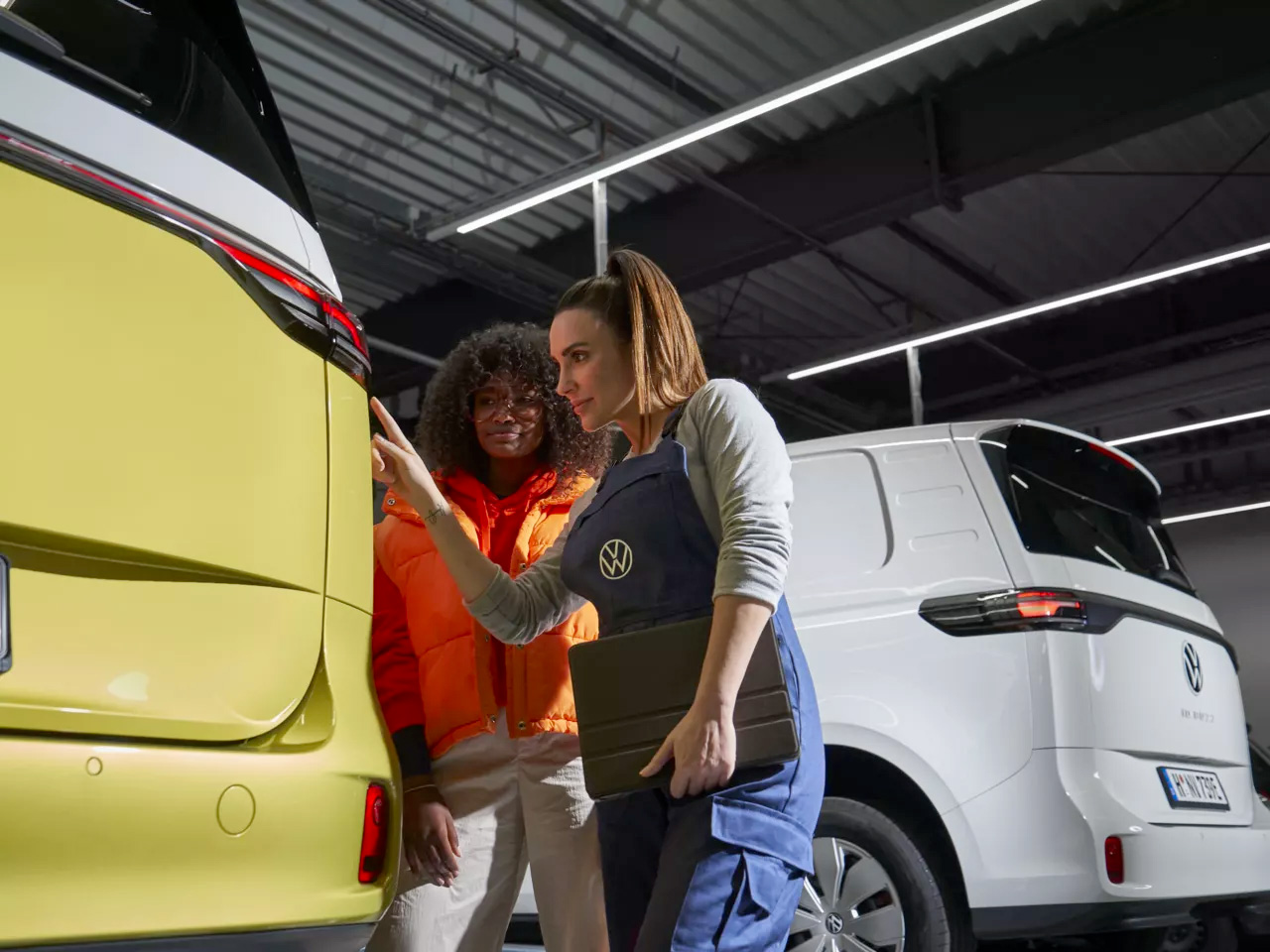 Un'addetta al lavoro ispezionana un veicolo illustrandolo al cliente