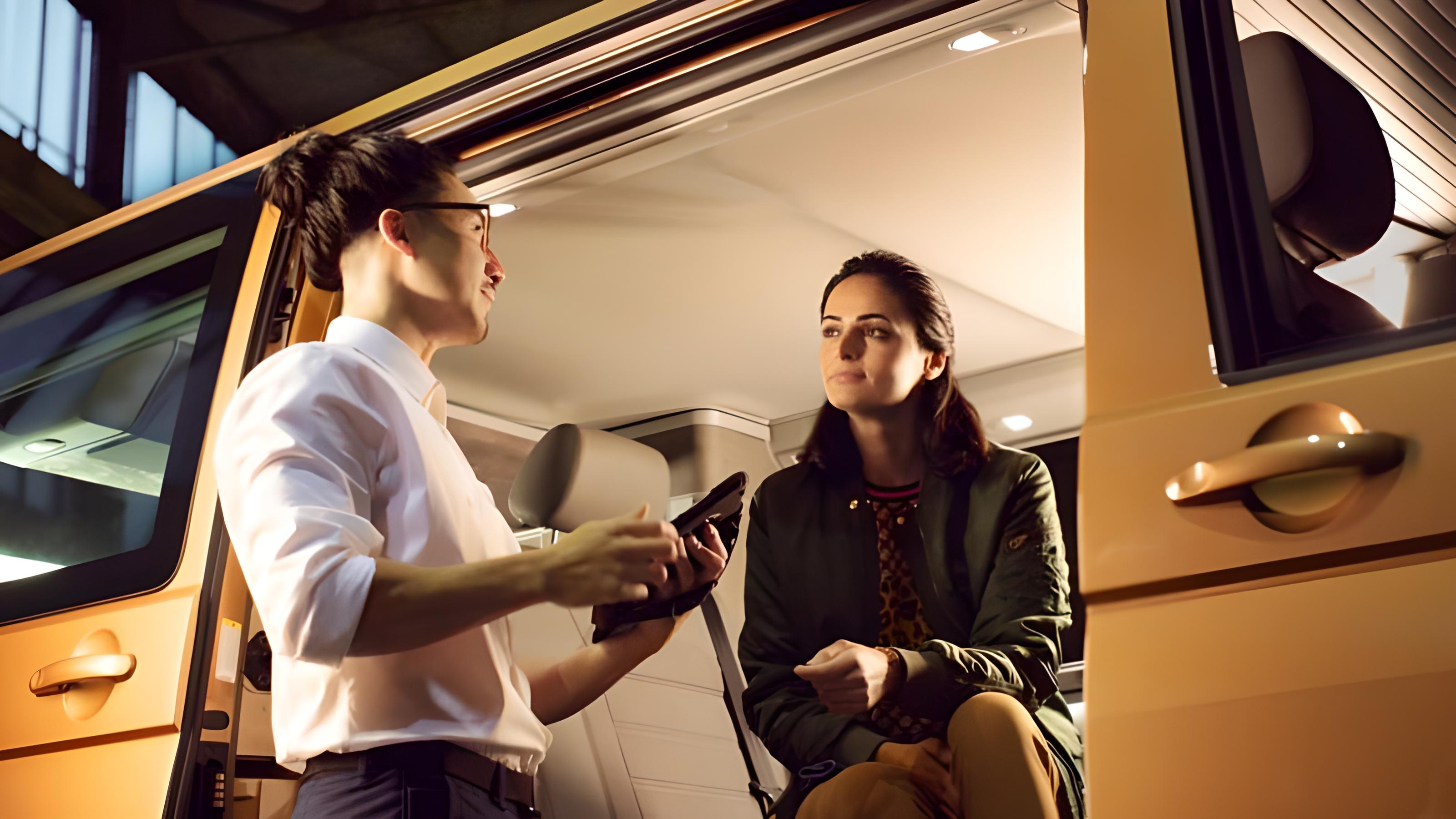 Un addetto VW si rivolge a una cliente seduta all'interno di un veicolo VW